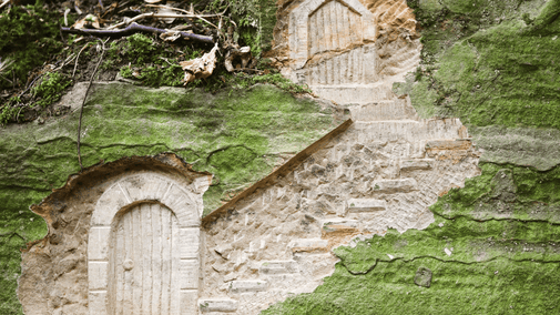 Two fairy doors carved into a mossy stone at Hardwick, Derbyshire
